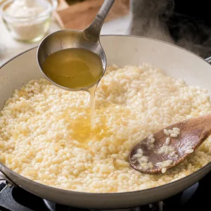 A ladleful of warm broth being added to creamy risotto