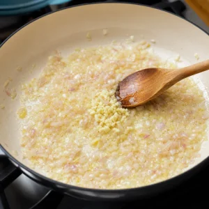Minced shallot and garlic sauteing in melted butter in a skillet