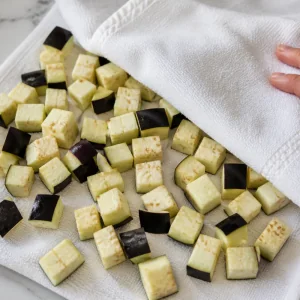 Eggplant cubes being dried with a clean towel