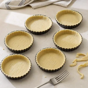 Six tartlet pans lined with pricked pastry dough