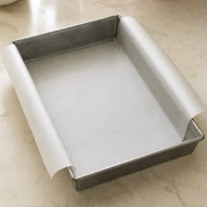 Metal baking pan lined with overhanging parchment