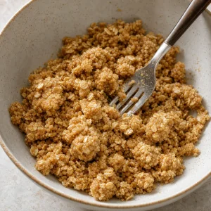 Moist oat crumble clumps in a bowl with a fork