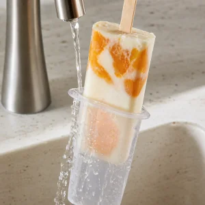 Peach yogurt pop released from its mold under warm water