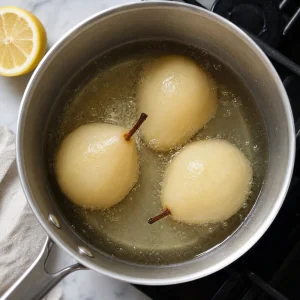 Peeled pears simmering in syrup in a saucepan