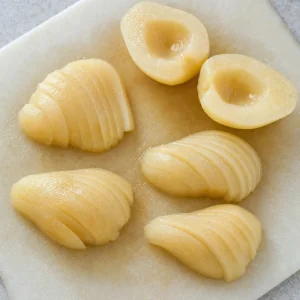 Poached pear halves cored and sliced on a cutting board