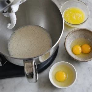 Mezcla de levadura espumosa en un bol de batidora con mantequilla y huevos cerca