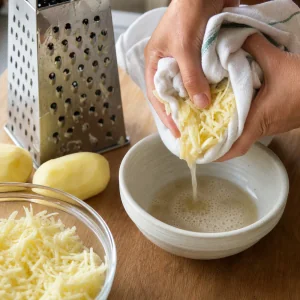 Grated potatoes being squeezed in a clean towel