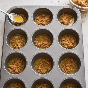 Muffin cups filled with melted butter and brown sugar.