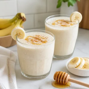 Due bicchieri di frullato cremoso banana miele e yogurt greco con fette di banana e miele