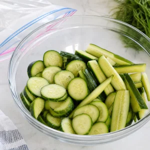Sliced cucumbers placed in a large mixing bowl for salted cucumber preparation