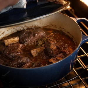 Tender braised short ribs in a Dutch oven after slow cooking in red wine sauce.