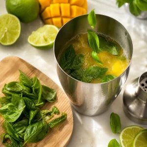 Fresh basil leaves added to the mango cocktail shaker