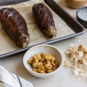 Peeled roasted garlic cloves ready while eggplants cool