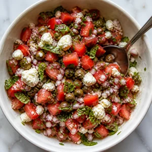 Tomato, mint, caper, onion, and cheese mixture in a bowl