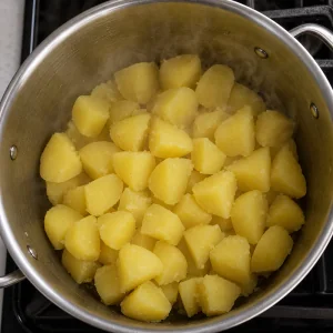 Trozos de papa escurridos soltando vapor en una olla caliente