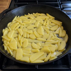 Patate a fette che friggono in olio caldo in padella