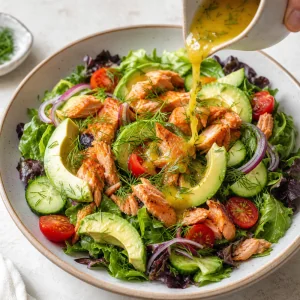Finished salmon avocado salad drizzled with citrus dressing and garnished with fresh dill