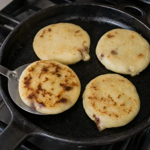 Pupusas rumieniące się na patelni żeliwnej