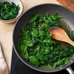 Spinach wilting in olive oil in a skillet
