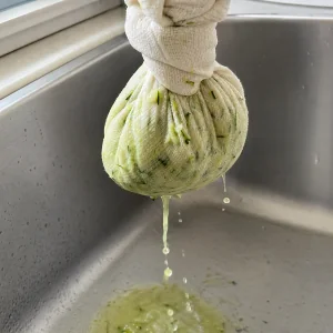 Curgete ralada a ser espremida num pano de cozinha