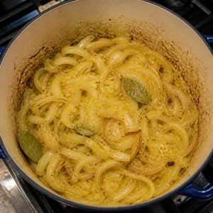 Sliced onions and bay leaves softening in the pot