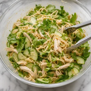 Nudeln mit Hähnchen, Gurke, Frühlingszwiebeln und Kräutern vermengt