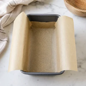 Small loaf pan lined with parchment paper and overhanging sides for tahini halva