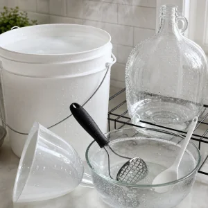 Sanitized winemaking bucket carboy funnel masher and spoon drying on a clean counter