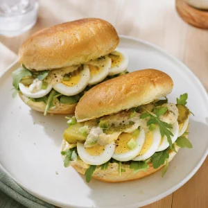 Fertige Eier-Sandwiches mit Rucola und Gurken auf getoasteten Brötchen