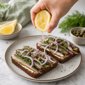 Squeezing lemon over a smoked sprat sandwich