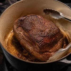 Seasoned beef roast browning in a Dutch oven