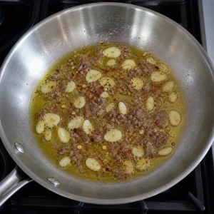 Chopped anchovies and red pepper flakes melting into garlic olive oil.