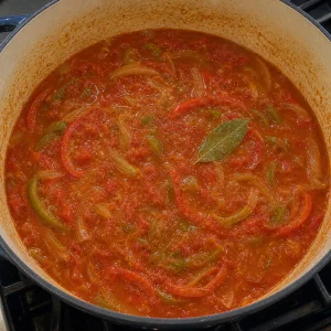 Salsa di pomodoro e peperoni che sobbolle con alloro