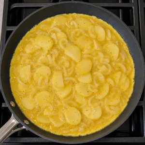 Egg, potato, and onion mixture spread in a skillet