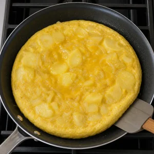 Spanish tortilla cooking with set edges and a soft center