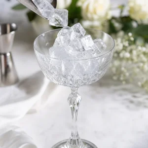 Kristall-Coupeglas mit Eis gefuellt, um es vor dem Mixen des Cocktails zu kuehlen