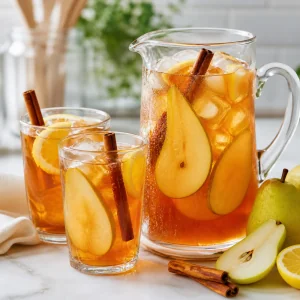 Vasos de té helado de pera especiada con hielo, pera y canela
