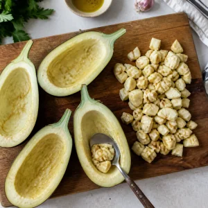 Le melanzane tagliate a metà vengono scavate con un cucchiaio, con la polpa tritata tenuta da parte per il ripieno.