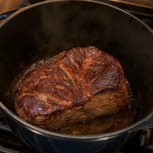 Deeply browned chuck roast searing in a Dutch oven