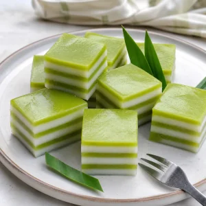 Carrés de gelée thaïe coco pandan avec des couches vertes de pandan et blanches de coco sur une assiette.