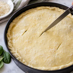 Cutting steam vents in the oiled top crust and sprinkling Parmesan before baking