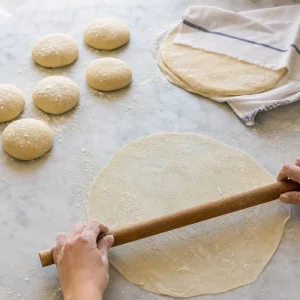 Rolling six pieces of dough into very thin rounds for the pastry layers