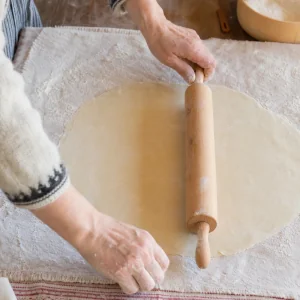Masa de lefse de patata extendida muy fina sobre un paño muy enharinado.