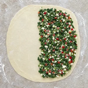 Recheio de espinafres e feta espalhado sobre metade da massa fina de gozleme