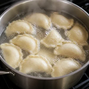 Varenyky a mezzaluna che galleggiano in acqua a leggero bollore.