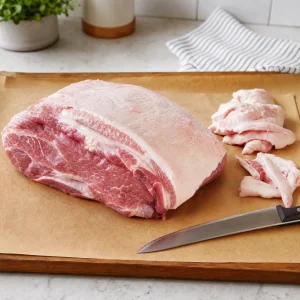 Raw pork shoulder trimmed on a cutting board with a small fat cap left