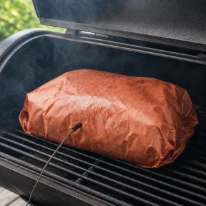 Wrapped pork shoulder returned to the smoker with a probe thermometer
