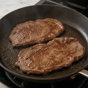 Thin steaks searing in a hot skillet
