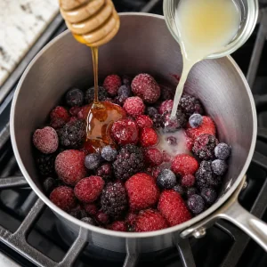 Mixed berries with honey and lemon juice in a saucepan