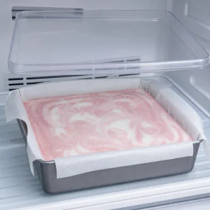 Firm marbled yogurt mixture freezing in a covered square pan.